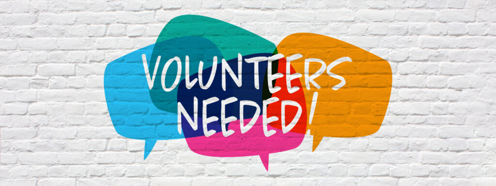 "Volunteers needed" against colorful speech bubbles on a white brick wall